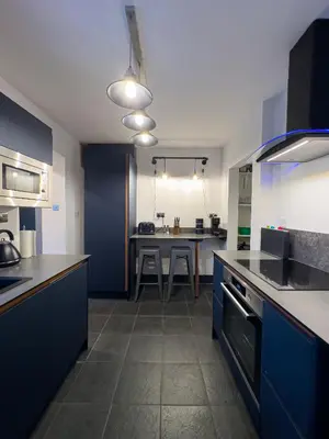 a kitchen with blue cabinets and a table in it at Coastal Lakes Mews Cottage