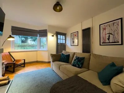 a living room with a couch and a window at Coastal Lakes Mews Cottage