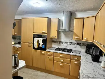 a kitchen with wooden cabinets and a stove top oven at Favourland Home in Moffat