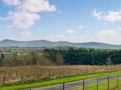 a road with a fence and mountains in the background at Miner's Rest in Frizington