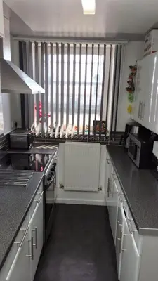 a kitchen with white cabinets and a large window at Pazuri Apart in Moffat
