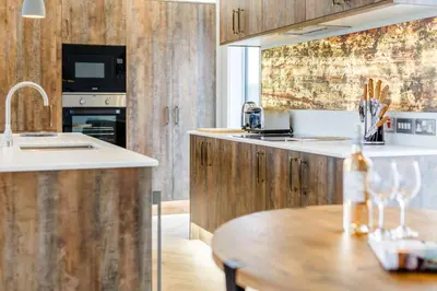 a kitchen with wooden cabinets and a wooden table at Landal North Lakes