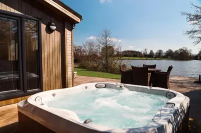a jacuzzi tub on a patio next to a lake at Landal North Lakes