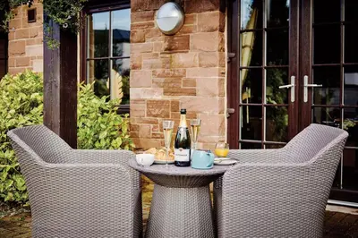 a table with two chairs and a bottle of wine at Landal Whitbarrow in Penruddock
