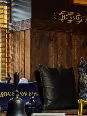 a room with a couch with pillows and a sign at Pink Cottage in Kirkcowan