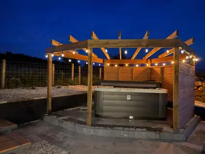 a hot tub in a wooden pergola at night at Woodway Lodge in Dumfries