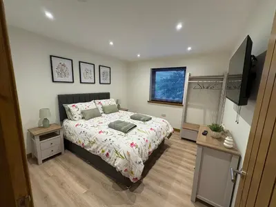 a bedroom with a bed and a flat screen tv at Woodway Lodge in Dumfries