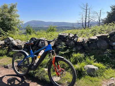 a bike parked next to a stone wall at Woodlane 3bedroom7 seater hottub and a pool table in Beeswing