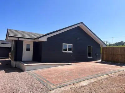 a black house with a driveway in front of it at Woodlane 3bedroom7 seater hottub and a pool table in Beeswing