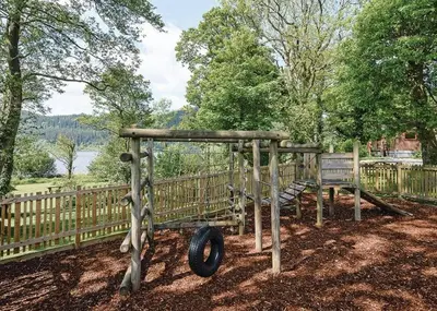 a playground with a tire and a wooden fence at Bassenthwaite Lakeside Lodges in Bassenthwaite