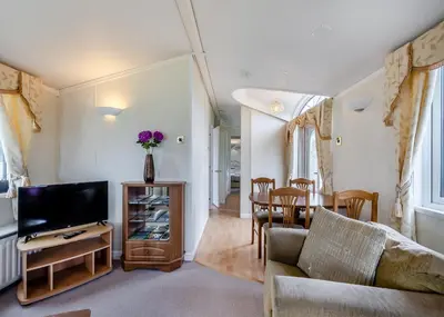 a living room with a couch and a tv and a table at Rowanbank Caravan Park in Beckfoot