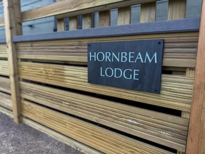 a sign on the side of a wooden fence at Hornbeam Lodge in Bassenthwaite