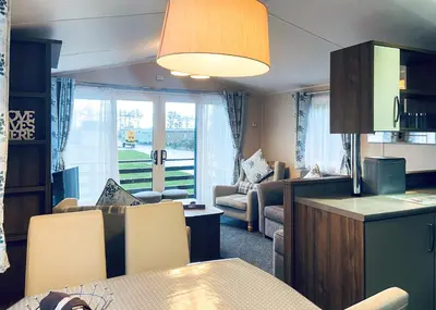 a kitchen and living room with a table and chairs at Whitecairn Holiday Park in Glenluce