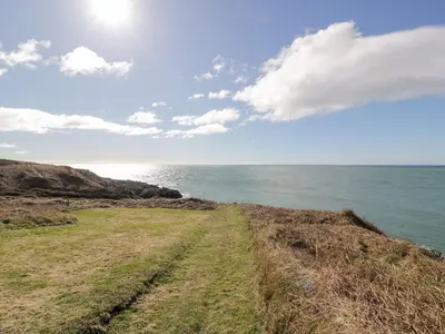 a dirt road next to the ocean on a hill at Peaceful in Stranraer