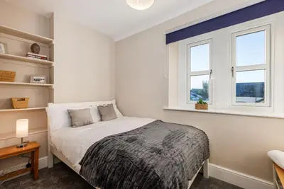 a bedroom with a bed and two windows at North Loft a Modern Apartment in Cockermouth in Cockermouth