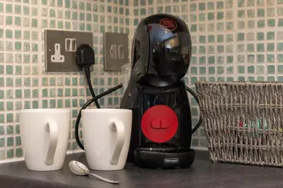 a black blender sitting on a counter with two white cups at North Loft a Modern Apartment in Cockermouth in Cockermouth