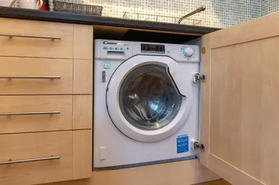 a washing machine in a cabinet in a kitchen at North Loft a Modern Apartment in Cockermouth in Cockermouth