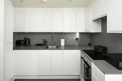 a kitchen with white cabinets and a sink at 1 Bed Flat in Shoreditch near Station by Hostroo in Moffat