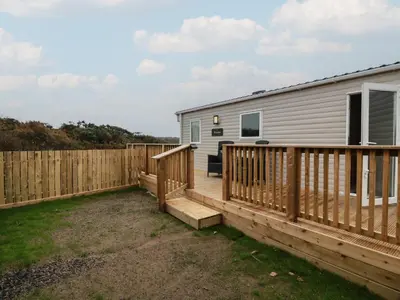 a deck with a house and a fence at Ellies House in Stranraer
