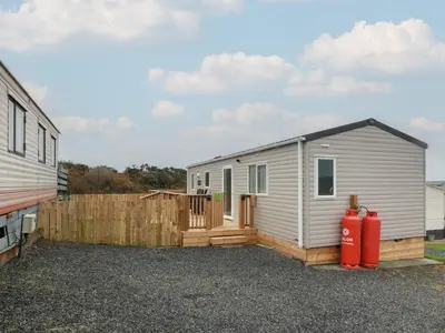 a small white trailer with a fence and a fire hydrant at Ellies House in Stranraer
