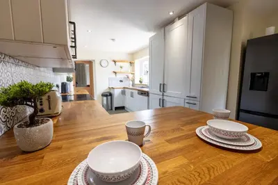 a kitchen with a wooden table with plates and cups on it at EASTCOTE FARM - Spacious 5-Bed Home with Views, Garden & Playroom in Silloth