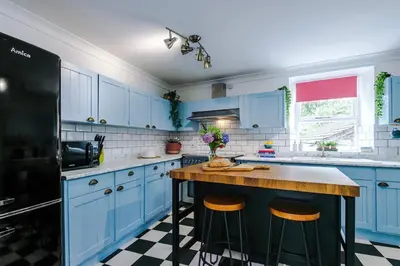 a kitchen with blue cabinets and a counter with stools at Springholm Cottage Family Retreat - Sleeps 10 in Bootle