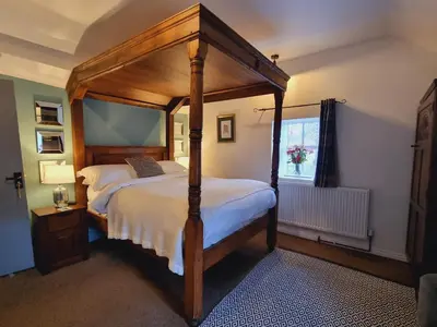 a bedroom with a canopy bed and a window at Lane Head Farm Country Guest House in Troutbeck