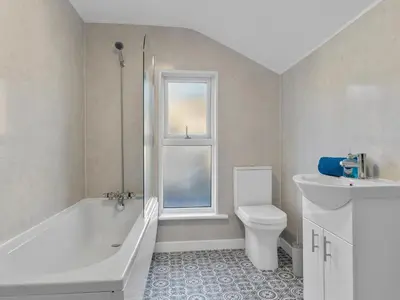 a bathroom with a tub and a toilet and a window at Harrington Haven - 4bed Home Workington in Workington