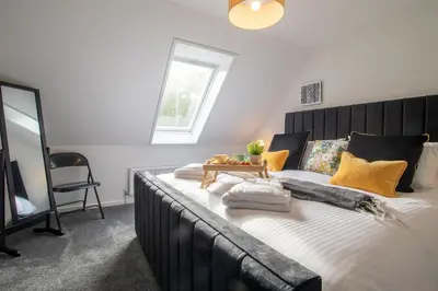 a bedroom with a large bed with yellow pillows at Corsehill Cottage - 3 Bedroom, 2 bathroom House in Dreghorn
