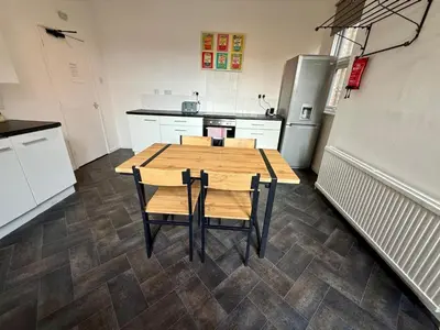 a kitchen with a wooden table and a refrigerator at Clapham Road Apartment in Moffat