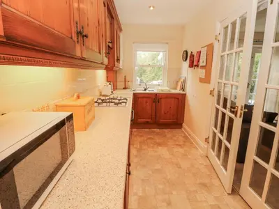 a large kitchen with wooden cabinets and a sink at Flat 17 Greta Grove in Keswick