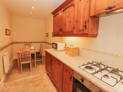 a kitchen with wooden cabinets and a stove top oven at Flat 17 Greta Grove in Keswick