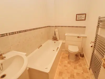 a bathroom with a tub and a toilet and a sink at Flat 17 Greta Grove in Keswick