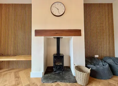 a fireplace in a living room with a clock on the wall at Jaytrees, Keswick - Luxury bungalow with hot tub in Keswick