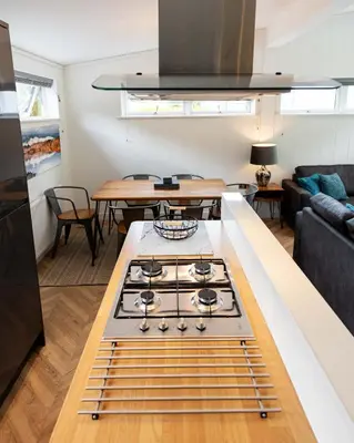 a kitchen with a stove and a living room at Great Gable Riverside Luxury Lodge in Keswick