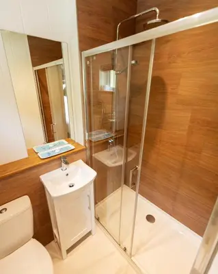 a bathroom with a shower and a toilet and a sink at Great Gable Riverside Luxury Lodge in Keswick