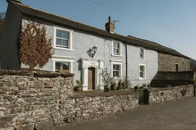 a white house with a stone wall at The Farmhouse at Highside Farm in Bassenthwaite