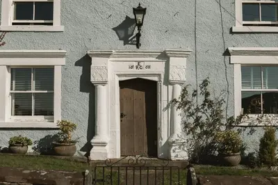 a white building with a wooden door in front at The Farmhouse at Highside Farm in Bassenthwaite