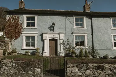 a blue house with a gate in front of it at The Farmhouse at Highside Farm in Bassenthwaite