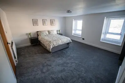 a bedroom with a bed and two windows at Cottage in Seaton in Siddick