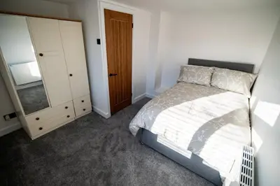 a bedroom with a bed and a dresser and a mirror at Cottage in Seaton in Siddick