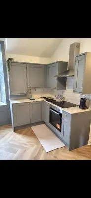 a kitchen with white cabinets and a stove top oven at Kirkgate 2 bed - Coorie Doon Stays in Irvine