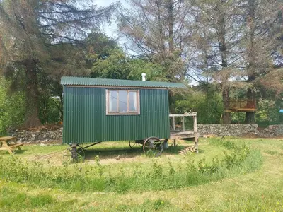 a green tiny house on a cart in a field at Shepherd's Hut Harmony at A Therapeutic Space in Moniaive