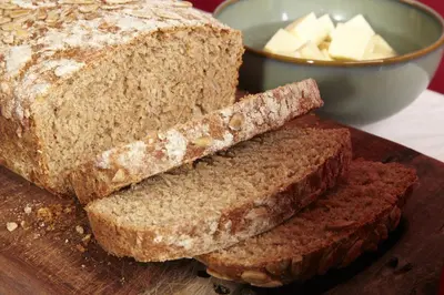 a loaf of bread on a cutting board with butter at Lowthwaite B&B in Watermillock