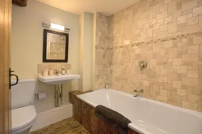 a bathroom with a tub and a sink and a toilet at Lowthwaite B&B in Watermillock