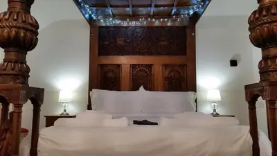 a bedroom with a large bed with a wooden headboard at Hot tub, Mountain View, 4-poster bed and log burner in Borrowdale Valley