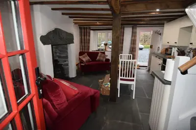 a living room with a red couch and a kitchen at Hot tub, Mountain View, 4-poster bed and log burner in Borrowdale Valley