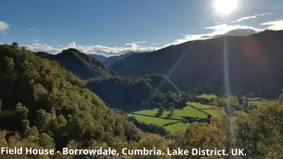 a view of a valley in the mountains with the sun at Hot tub, Mountain View, 4-poster bed and log burner in Borrowdale Valley