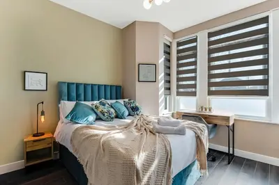 a bedroom with a bed with a blue headboard and a window at Stylish Studio Retreat in Ideal Location in Moffat
