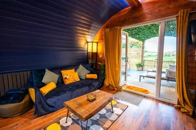 a living room with a couch and a table at Coorie Retreats Luxury Geo Domes and Cabins with Private Hot Tubs Cinema Firepit Spa and More in Portpatrick